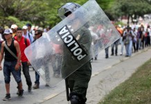 Un policía camina junto a varios campesinos que participan en una marcha en Cali (Colombia). EFE/Archivo