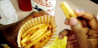 Una mujer sin identificar come patatas fritas en un restaurante. Archivo
